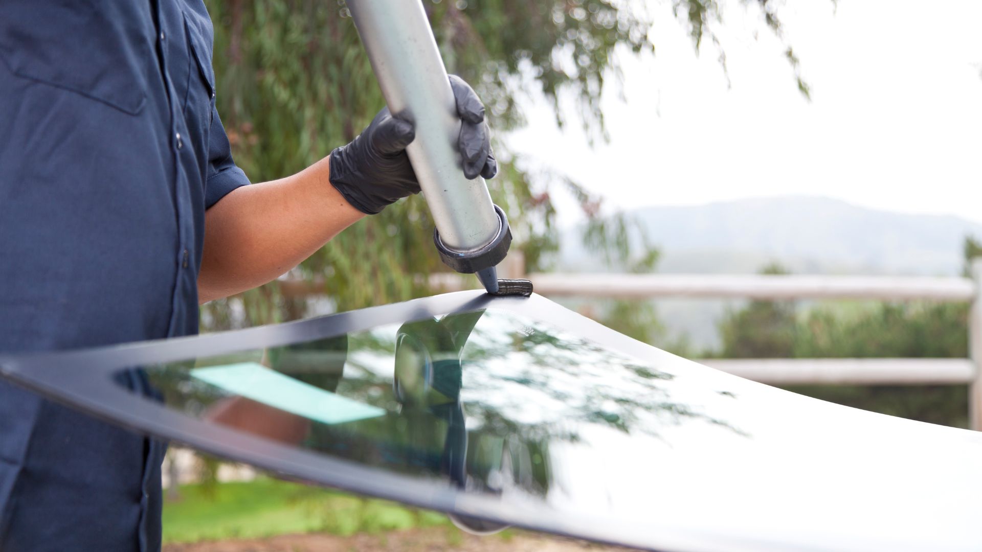 Gloved hand using windshield wiper on car glass with outdoor background